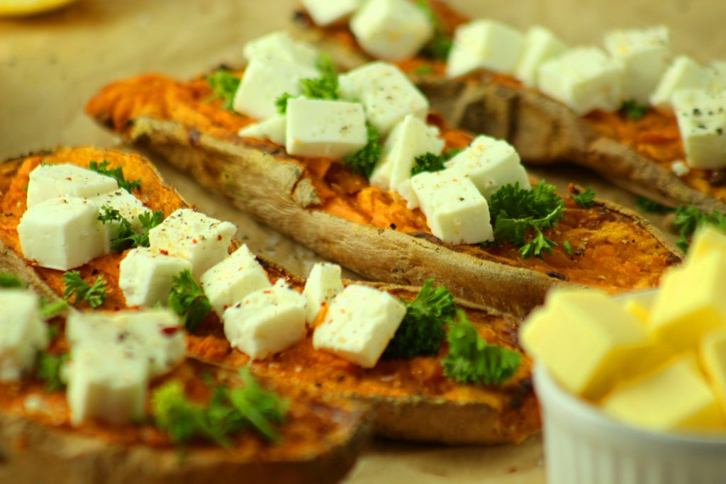 mehrere Süßkartoffelhälften mit Feta und Petersilie belegt